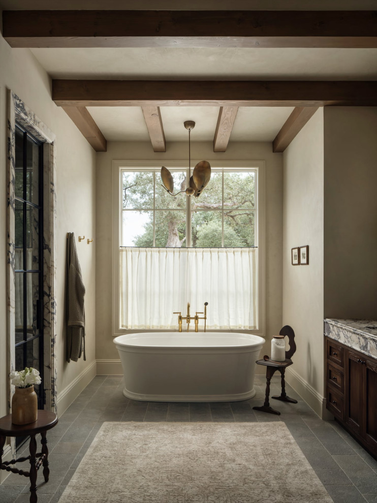 Example of a transitional master gray floor and exposed beam freestanding bathtub design in Austin with shaker cabinets, dark wood cabinets, beige walls, an undermount sink, a hinged shower door, gray countertops and a built-in vanity