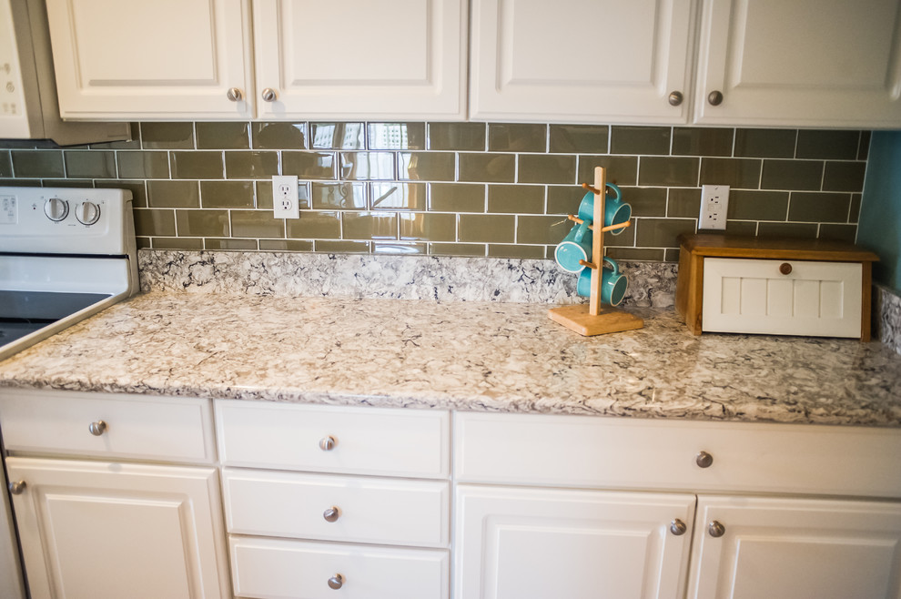 Eat-in kitchen - small transitional u-shaped ceramic tile eat-in kitchen idea with a drop-in sink, raised-panel cabinets, white cabinets, granite countertops, brown backsplash, porcelain backsplash, white appliances and an island