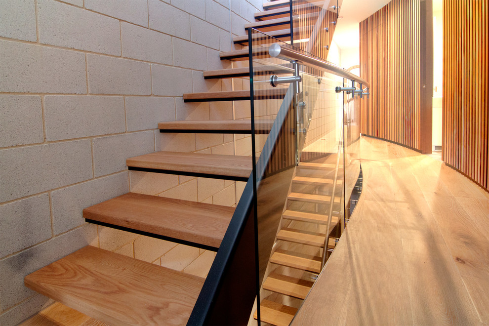Photo of a mid-sized contemporary wood straight staircase in Other with open risers and glass railing.
