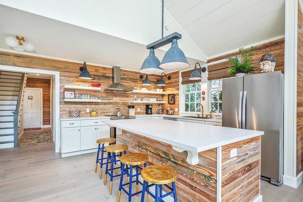 Inspiration for a beach style l-shaped open plan kitchen in Miami with recessed-panel cabinets, distressed cabinets, brown splashback, timber splashback, stainless steel appliances, with island, grey floor and white benchtop.