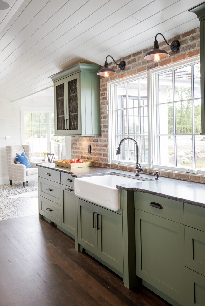Inspiration for a country galley kitchen in Other with a farmhouse sink, shaker cabinets, green cabinets, granite benchtops, brick splashback, stainless steel appliances, dark hardwood floors and brown floor.