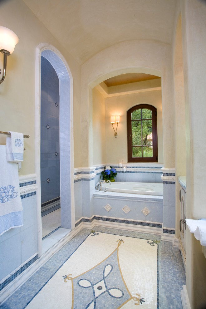 Design ideas for a traditional bathroom in Denver with a drop-in tub and blue tile.