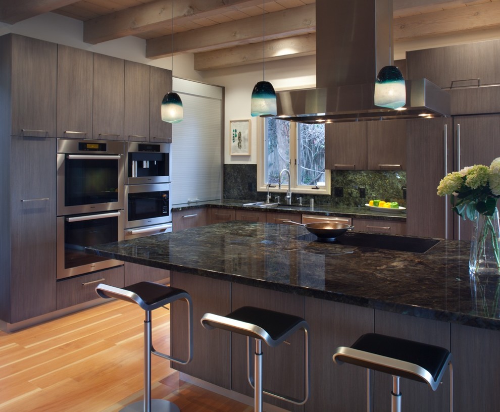 Design ideas for a large modern u-shaped kitchen in San Diego with flat-panel cabinets, grey cabinets, granite benchtops, stainless steel appliances, light hardwood floors, with island, stone slab splashback and an undermount sink.