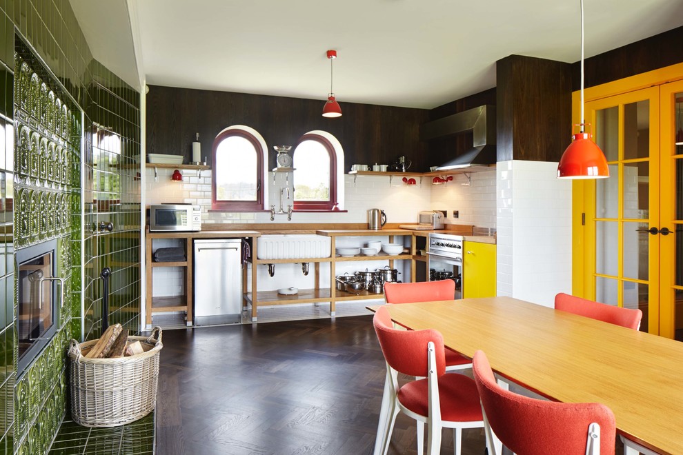 Design ideas for a mid-sized eclectic single-wall eat-in kitchen in Essex with a farmhouse sink, open cabinets, medium wood cabinets, wood benchtops, white splashback, subway tile splashback, stainless steel appliances, dark hardwood floors and no island.