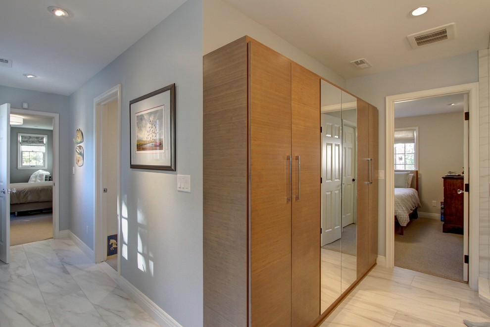 This is an example of a mid-sized transitional gender-neutral built-in wardrobe in Denver with flat-panel cabinets, medium wood cabinets, marble floors and grey floor.