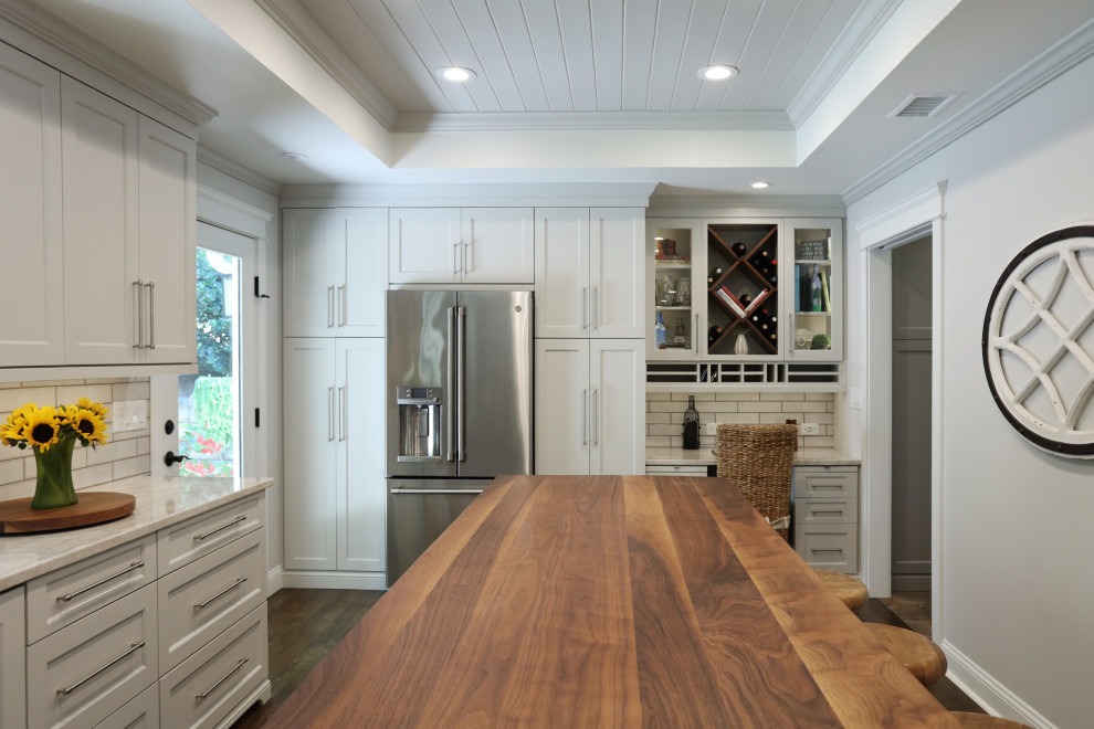 Inspiration for a mid-sized traditional u-shaped eat-in kitchen in Atlanta with an undermount sink, recessed-panel cabinets, white cabinets, quartzite benchtops, white splashback, porcelain splashback, stainless steel appliances, medium hardwood floors, with island, brown floor, beige benchtop and coffered.