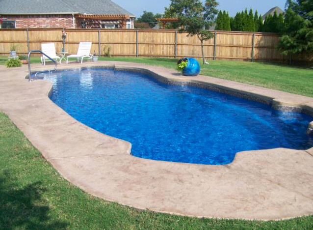 Example of a large backyard stamped concrete and custom-shaped natural pool design in Cincinnati