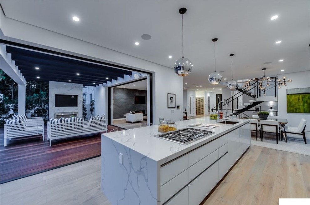 Mid-sized modern galley eat-in kitchen in Los Angeles with an undermount sink, flat-panel cabinets, white cabinets, marble benchtops, bamboo floors, with island, beige floor, white benchtop and stainless steel appliances.