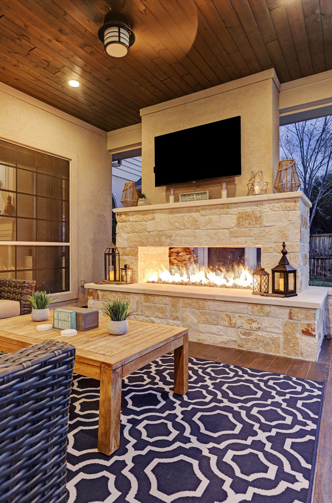 Inspiration for a mid-sized country backyard patio in Houston with with fireplace, tile and a roof extension.