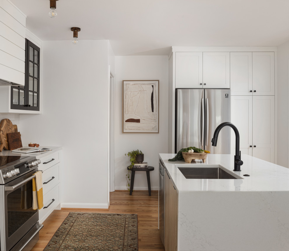 Example of a small minimalist l-shaped light wood floor and brown floor eat-in kitchen design in DC Metro with an undermount sink, shaker cabinets, black cabinets, quartz countertops, gray backsplash, ceramic backsplash, stainless steel appliances, an island and white countertops