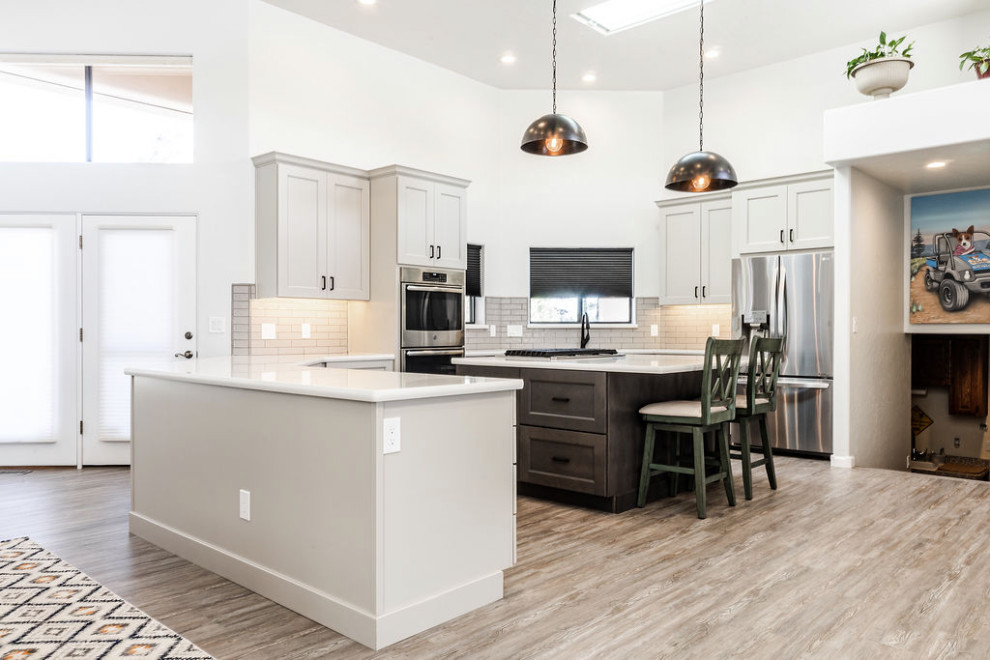 Example of a large transitional u-shaped vinyl floor and gray floor eat-in kitchen design with an undermount sink, shaker cabinets, gray cabinets, quartzite countertops, green backsplash, subway tile backsplash, stainless steel appliances, an island and white countertops