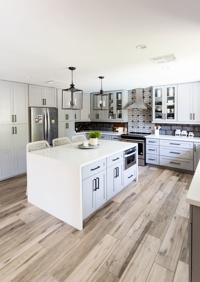 Inspiration for a mid-sized transitional u-shaped light wood floor and gray floor eat-in kitchen remodel in Phoenix with an undermount sink, recessed-panel cabinets, gray cabinets, quartz countertops, multicolored backsplash, ceramic backsplash, stainless steel appliances, an island and white countertops