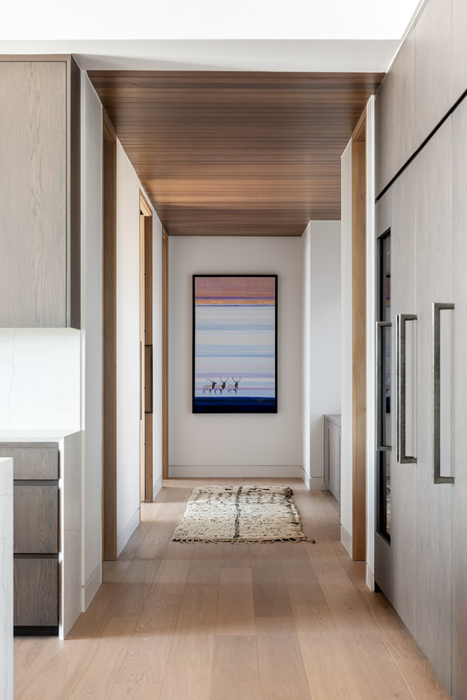 Cette photo montre un couloir moderne avec un mur blanc, parquet clair et un plafond en bois.