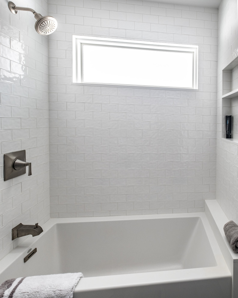 Small transitional bathroom in New York with shaker cabinets, blue cabinets, a drop-in tub, a shower/bathtub combo, a two-piece toilet, white tile, porcelain tile, grey walls, porcelain floors, an undermount sink, quartzite benchtops, grey floor, a shower curtain and white benchtops.