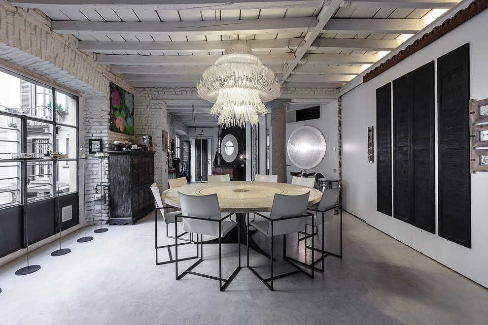 This is an example of a large industrial dining room in Milan with white walls and concrete floors.