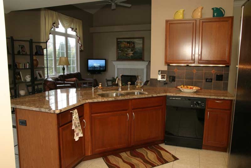 Transitional u-shaped medium tone wood floor kitchen pantry photo in Chicago with raised-panel cabinets, medium tone wood cabinets and granite countertops