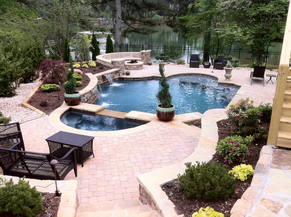 Inspiration for a mid-sized traditional backyard custom-shaped natural pool in Atlanta with a water feature and brick pavers.