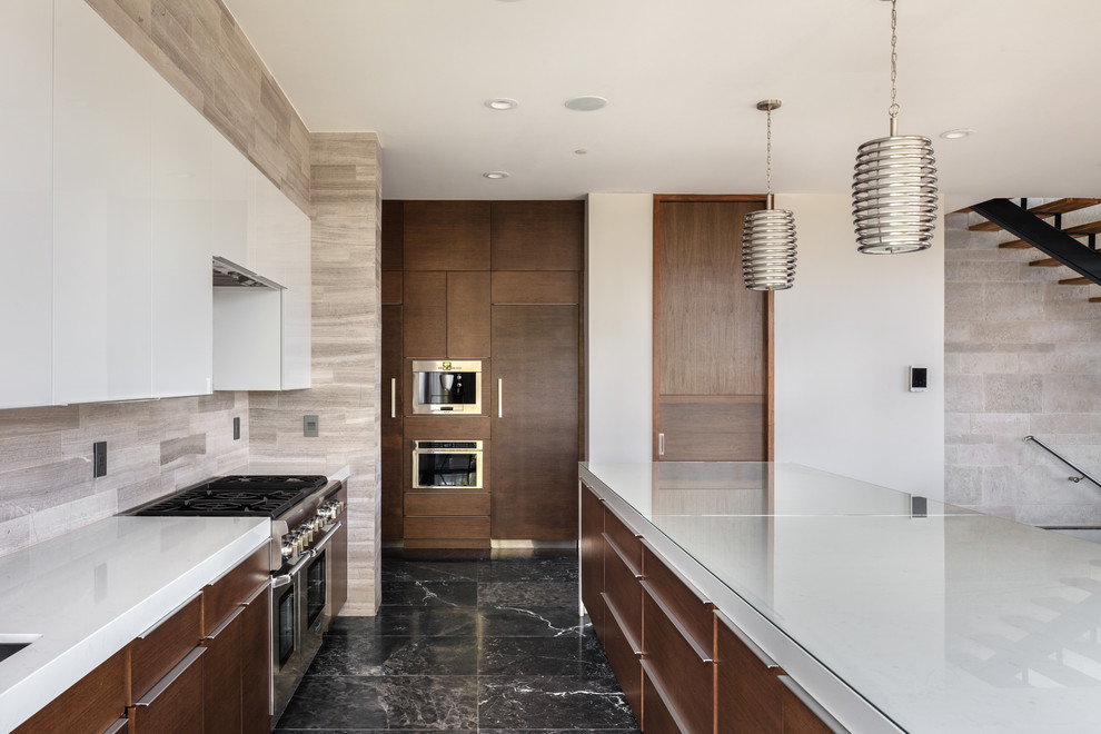 This is an example of a contemporary open plan kitchen in Austin with flat-panel cabinets, white cabinets, grey splashback, stainless steel appliances, with island, black floor, white benchtop and marble floors.