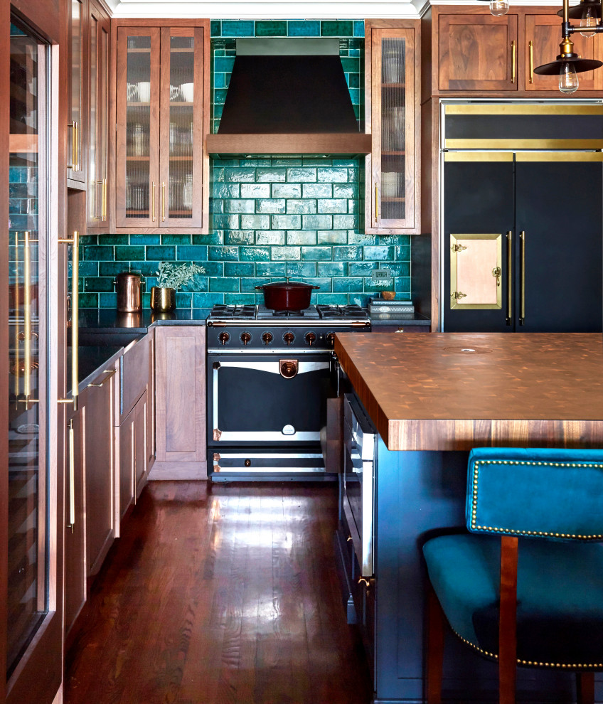 Klassische Küche mit hellbraunen Holzschränken, Küchenrückwand in Grün, Rückwand aus Metrofliesen, schwarzen Elektrogeräten, braunem Holzboden und Kücheninsel in Chicago