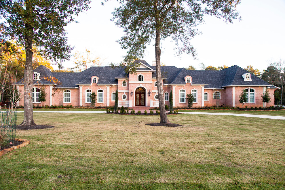 Photo of a large traditional one-storey brick red exterior in Houston with a clipped gable roof.