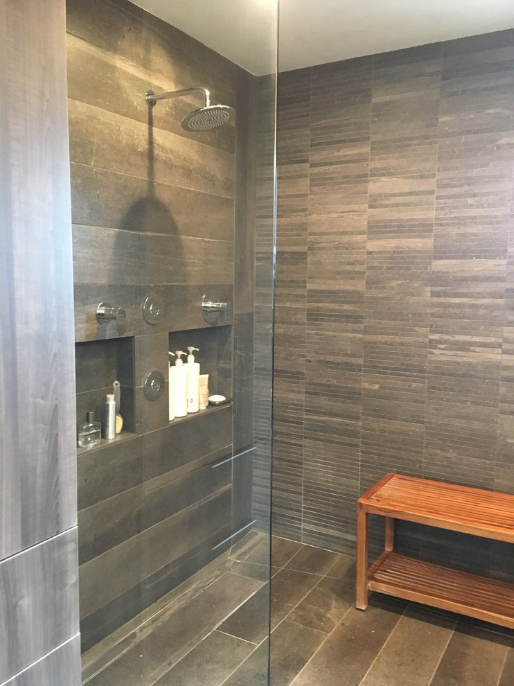 This is an example of a mid-sized contemporary master wet room bathroom in Chicago with flat-panel cabinets, grey cabinets, a freestanding tub, a wall-mount toilet, gray tile, porcelain tile, grey walls, porcelain floors, an integrated sink, engineered quartz benchtops, grey floor and a hinged shower door.