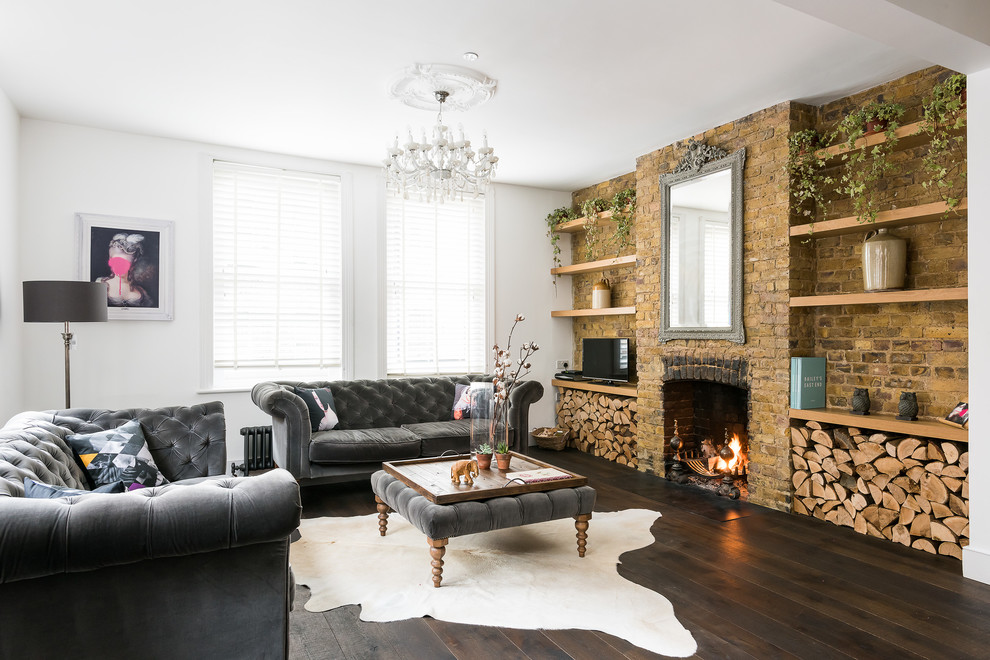Inspiration for a mid-sized enclosed living room in London with white walls, dark hardwood floors, a standard fireplace, a brick fireplace surround, a freestanding tv and brown floor.
