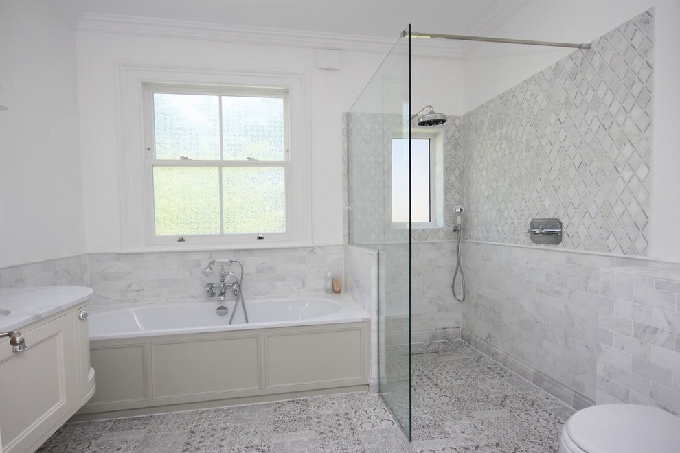 This is an example of a large traditional master wet room bathroom in Other with a corner tub, a wall-mount toilet, gray tile, porcelain tile, white walls, marble benchtops, grey floor, an open shower, white benchtops, shaker cabinets, beige cabinets, porcelain floors and a drop-in sink.