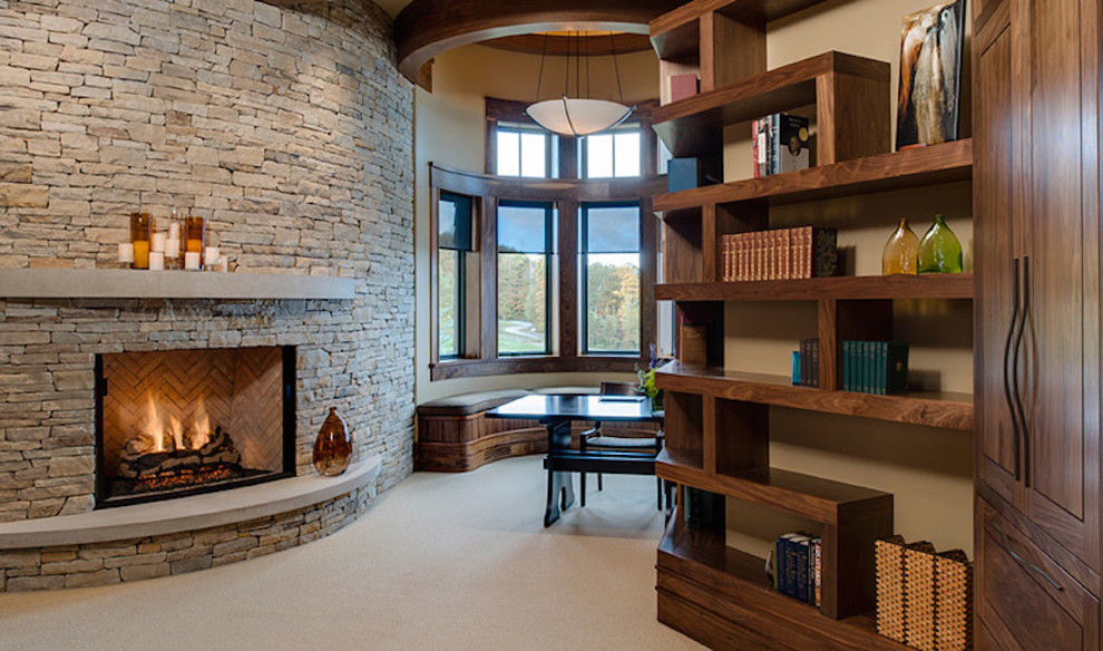 Photo of a large traditional home office in Other with beige walls, carpet, a standard fireplace, a stone fireplace surround and a freestanding desk.