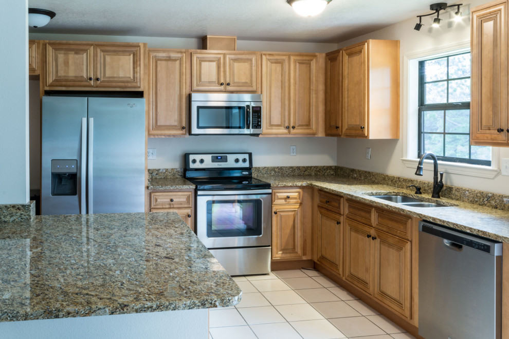 Example of a mid-sized l-shaped eat-in kitchen design with an undermount sink, raised-panel cabinets, medium tone wood cabinets, granite countertops, ceramic backsplash, stainless steel appliances, a peninsula and brown countertops