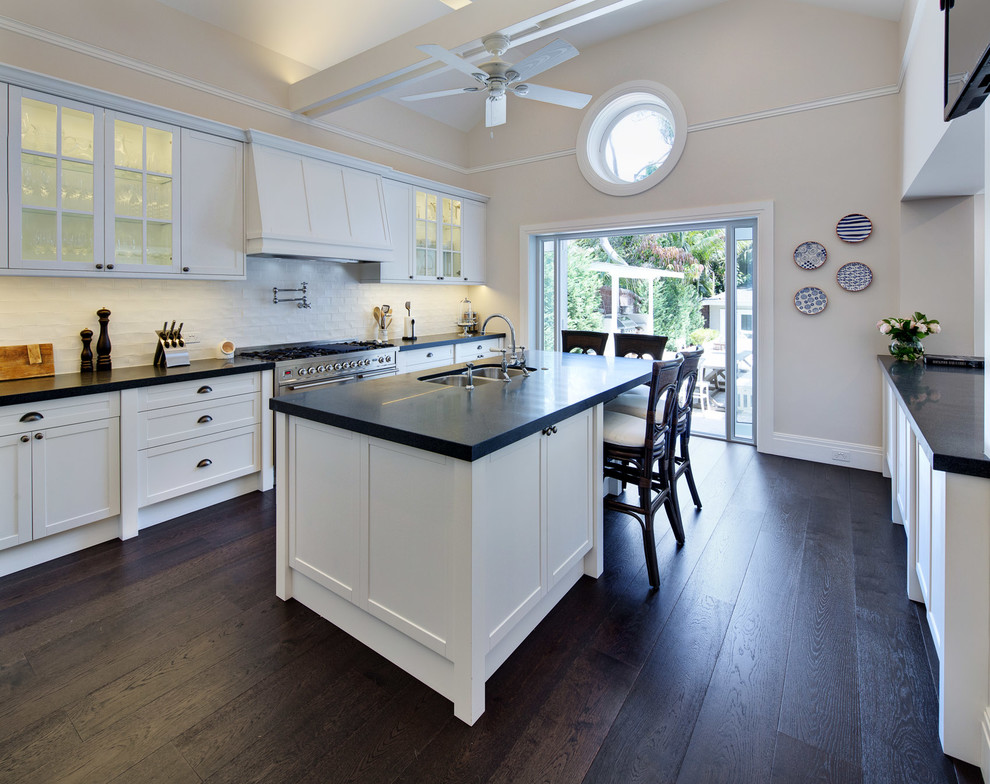 Photo of a large traditional kitchen in Sydney with a double-bowl sink, shaker cabinets, white cabinets, quartz benchtops, white splashback, ceramic splashback, stainless steel appliances, dark hardwood floors and with island.