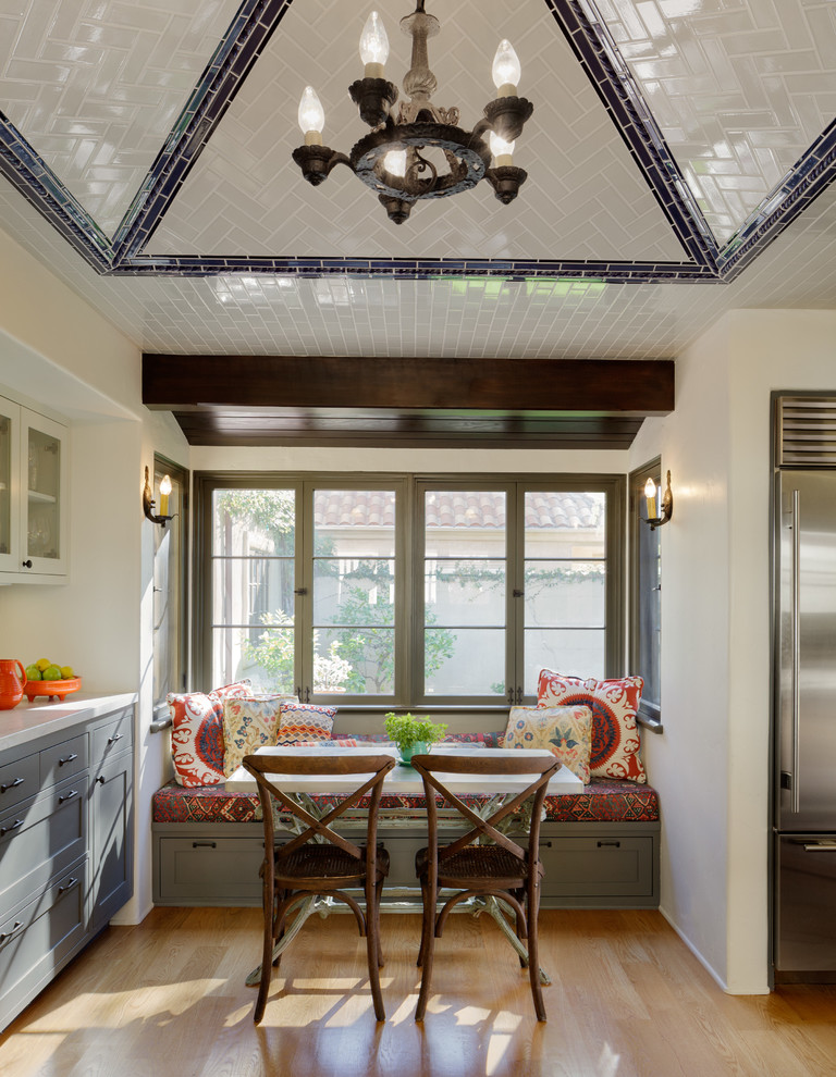 This is an example of a mediterranean u-shaped eat-in kitchen in Los Angeles with recessed-panel cabinets, grey cabinets, marble benchtops, white splashback, subway tile splashback and stainless steel appliances.