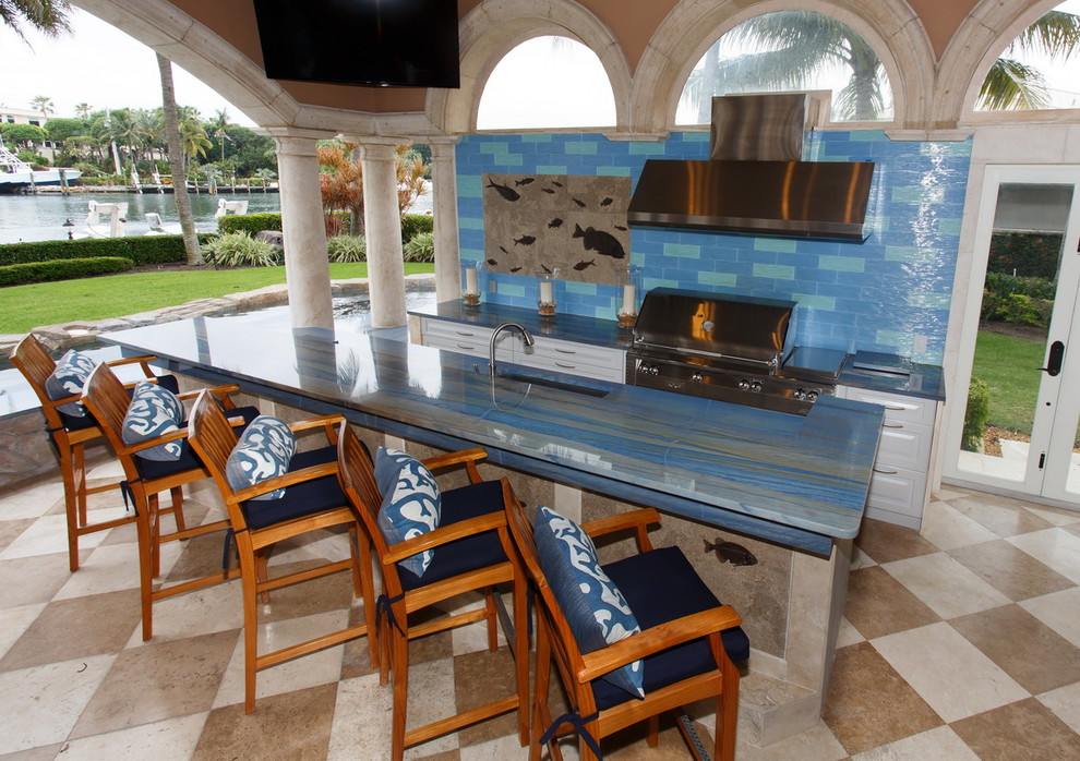 This is an example of a tropical backyard patio in Miami with an outdoor kitchen, tile and a roof extension.