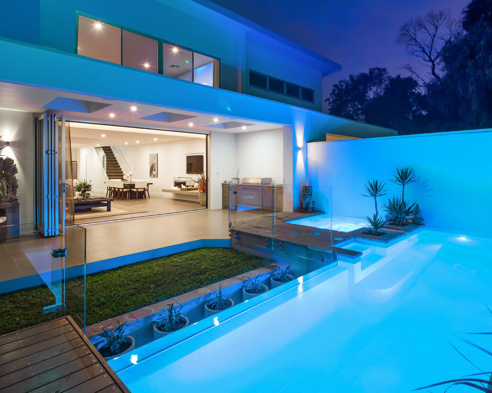 Photo of a contemporary backyard custom-shaped lap pool in Adelaide with tile and a hot tub.