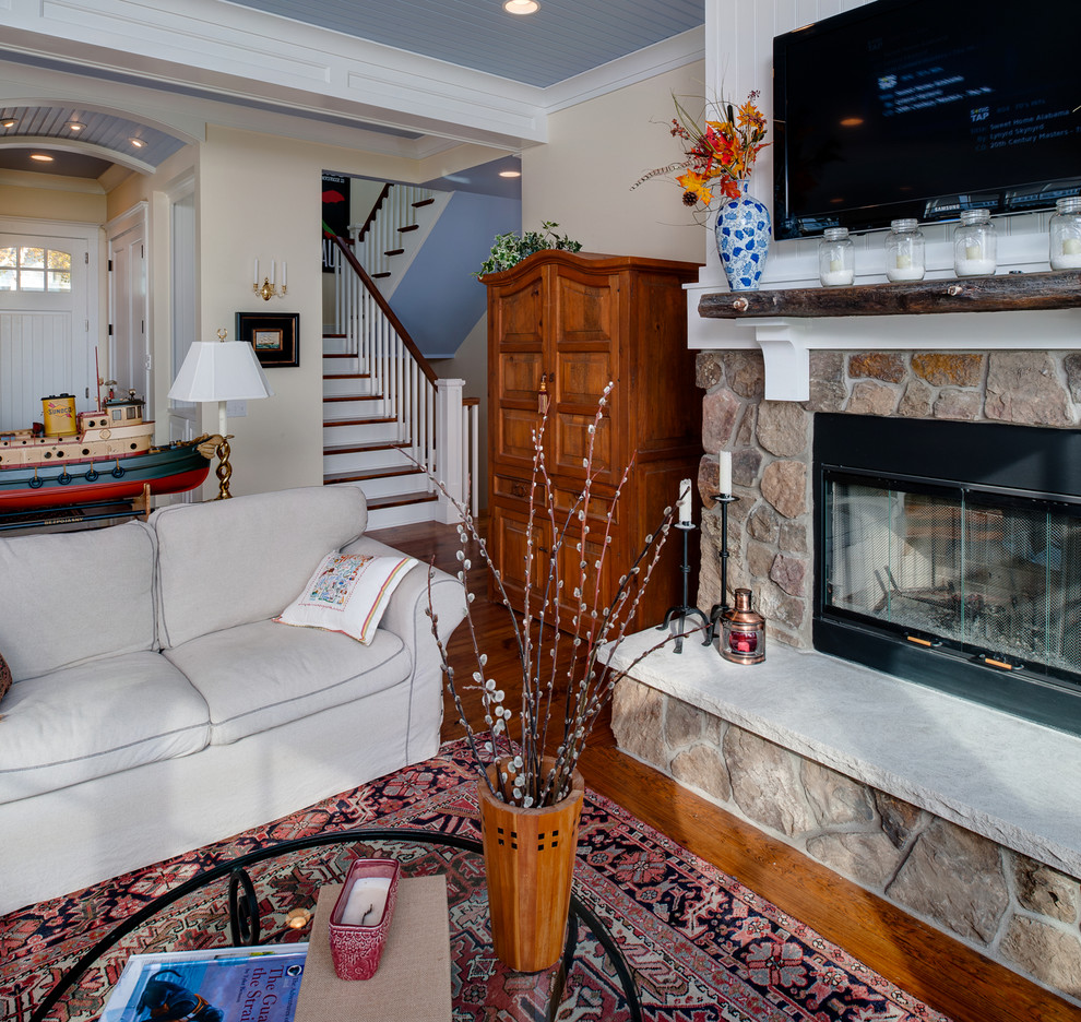 This is an example of a mid-sized arts and crafts open concept living room in Other with white walls, light hardwood floors, a standard fireplace, a stone fireplace surround, a wall-mounted tv, brown floor and timber.