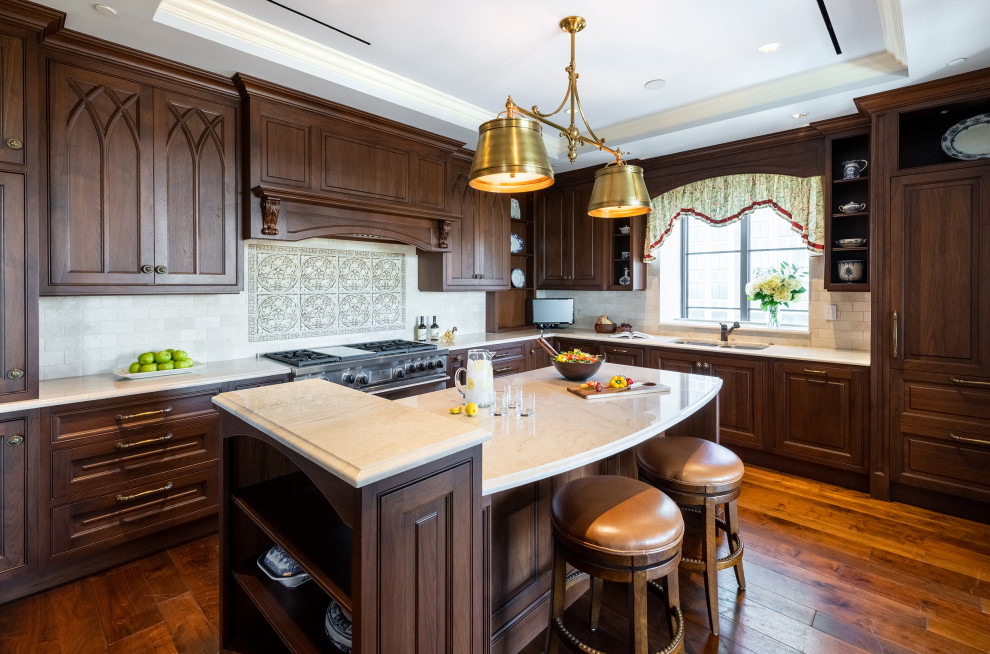 Photo of a large traditional l-shaped kitchen in Atlanta with an undermount sink, raised-panel cabinets, medium wood cabinets, grey splashback, panelled appliances, medium hardwood floors, with island, brown floor and grey benchtop.