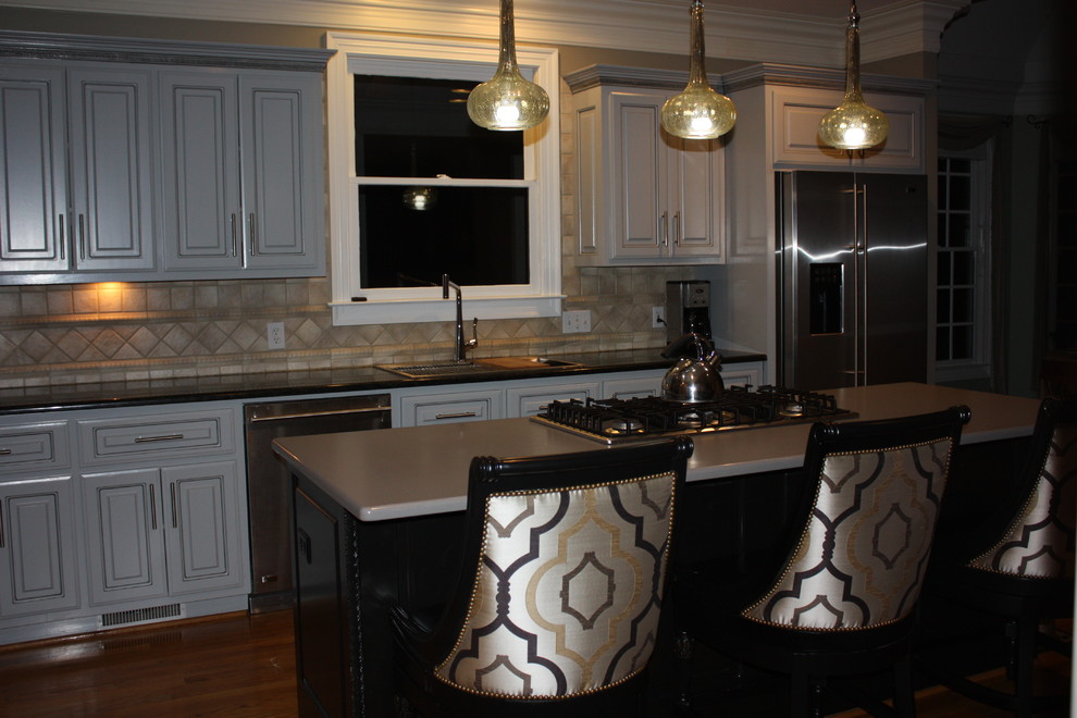 Large transitional u-shaped light wood floor eat-in kitchen photo with a double-bowl sink, raised-panel cabinets, gray cabinets, quartz countertops, beige backsplash, ceramic backsplash, stainless steel appliances and an island