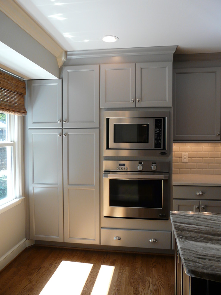Eat-in kitchen - huge transitional single-wall medium tone wood floor eat-in kitchen idea in Birmingham with an undermount sink, recessed-panel cabinets, gray cabinets, quartzite countertops, gray backsplash, porcelain backsplash, stainless steel appliances, gray walls and an island