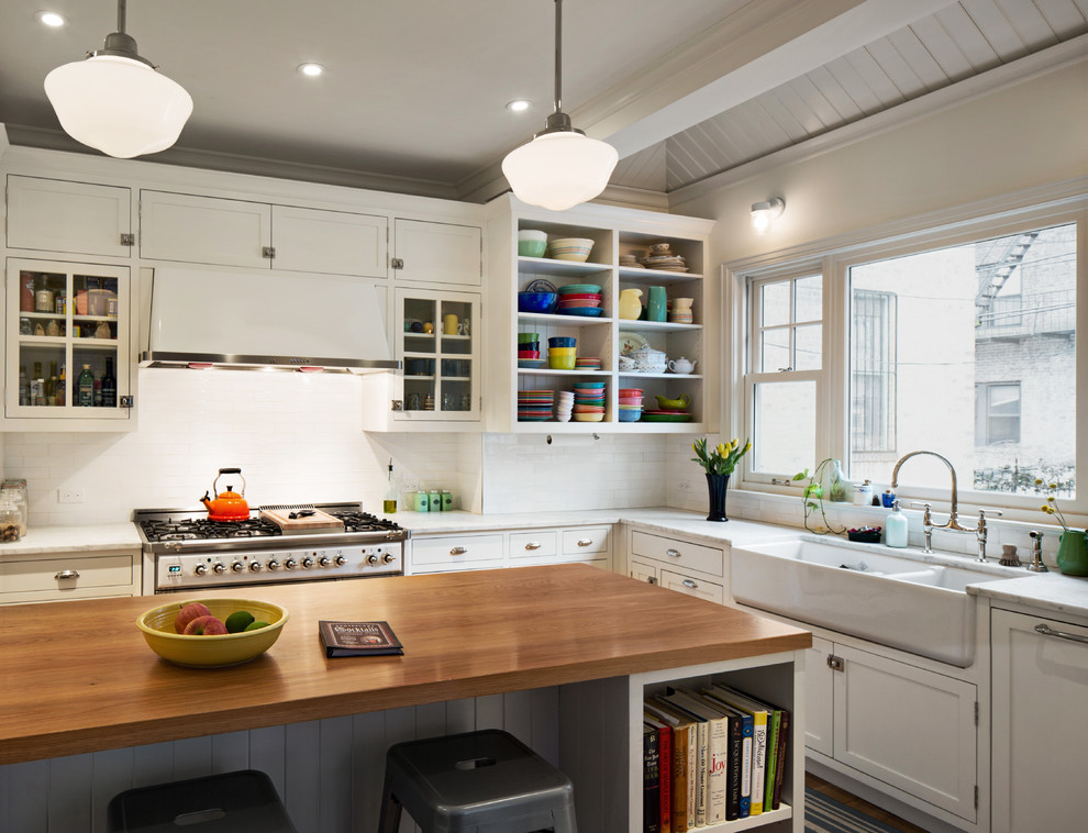 Design ideas for a mid-sized traditional l-shaped separate kitchen in New York with a farmhouse sink, shaker cabinets, white cabinets, marble benchtops, white splashback, subway tile splashback, white appliances, medium hardwood floors and with island.