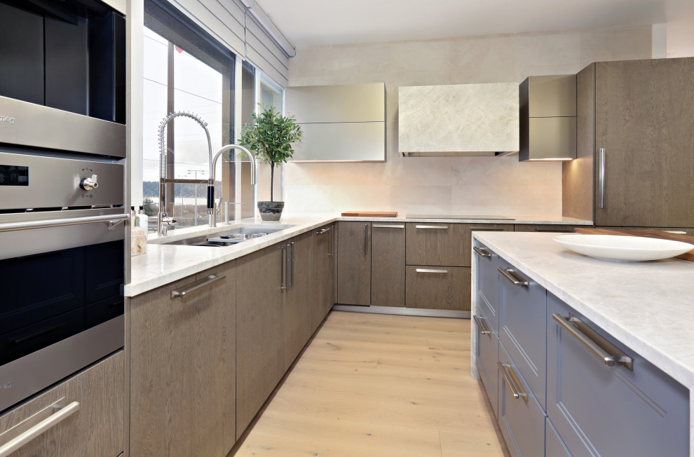 Mid-sized transitional l-shaped light wood floor and beige floor open concept kitchen photo in Seattle with an undermount sink, flat-panel cabinets, gray cabinets, quartzite countertops, beige backsplash, limestone backsplash, stainless steel appliances, an island and beige countertops