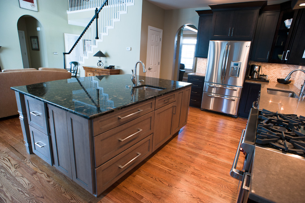 Kitchen - mid-sized transitional l-shaped kitchen idea in Charlotte with dark wood cabinets, granite countertops, white backsplash and an island
