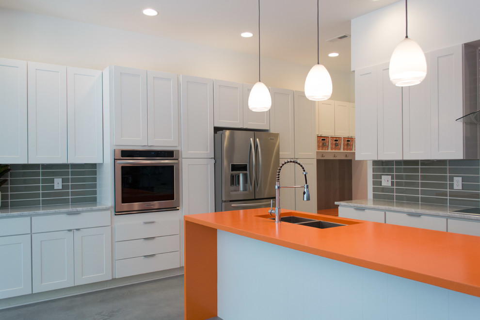 Design ideas for a contemporary l-shaped open plan kitchen in Raleigh with a double-bowl sink, flat-panel cabinets, white cabinets, marble benchtops, glass tile splashback, stainless steel appliances, marble floors, with island and grey splashback.