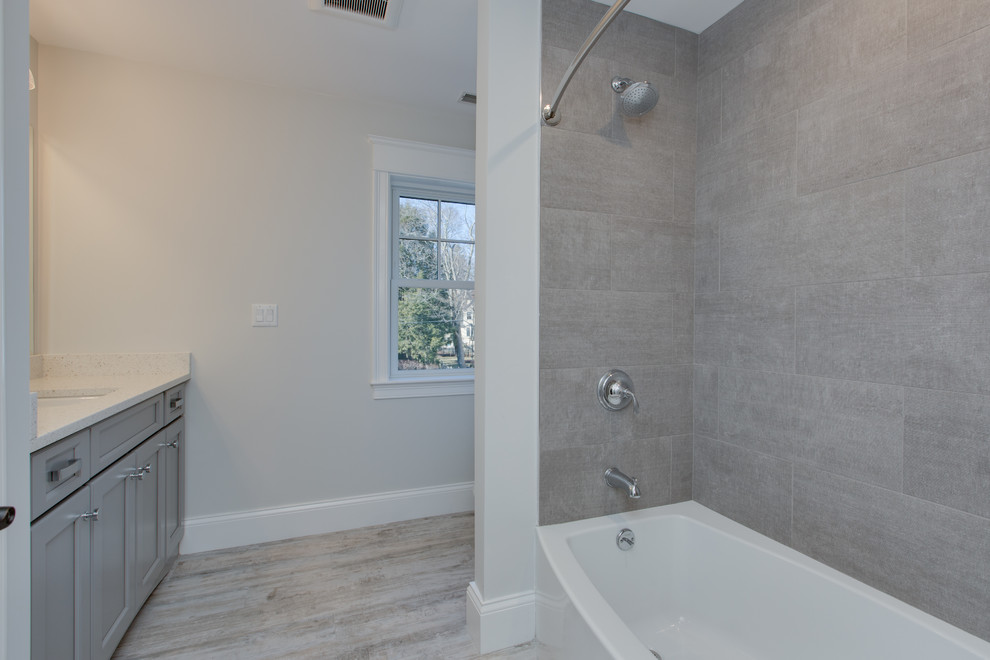 This is an example of a large transitional kids bathroom in Boston with shaker cabinets, grey cabinets, an alcove tub, a shower/bathtub combo, gray tile, grey walls, an undermount sink, granite benchtops, a shower curtain and white benchtops.