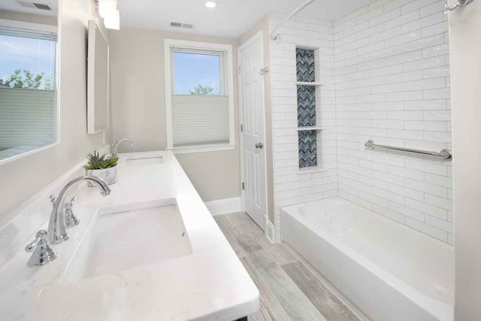 Klassisk inredning av ett mellanstort vit vitt badrum med dusch, med skåp i shakerstil, blå skåp, ett badkar i en alkov, en dusch/badkar-kombination, en toalettstol med separat cisternkåpa, vit kakel, keramikplattor, beige väggar, ett undermonterad handfat, bänkskiva i kvarts, beiget golv och dusch med duschdraperi