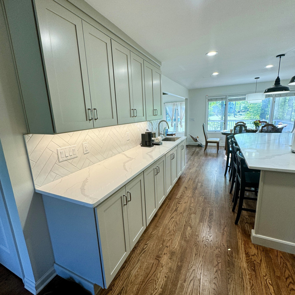 Inspiration for a mid-sized transitional u-shaped medium tone wood floor and brown floor open concept kitchen remodel in Atlanta with an undermount sink, shaker cabinets, beige cabinets, granite countertops, white backsplash, stainless steel appliances, an island and white countertops