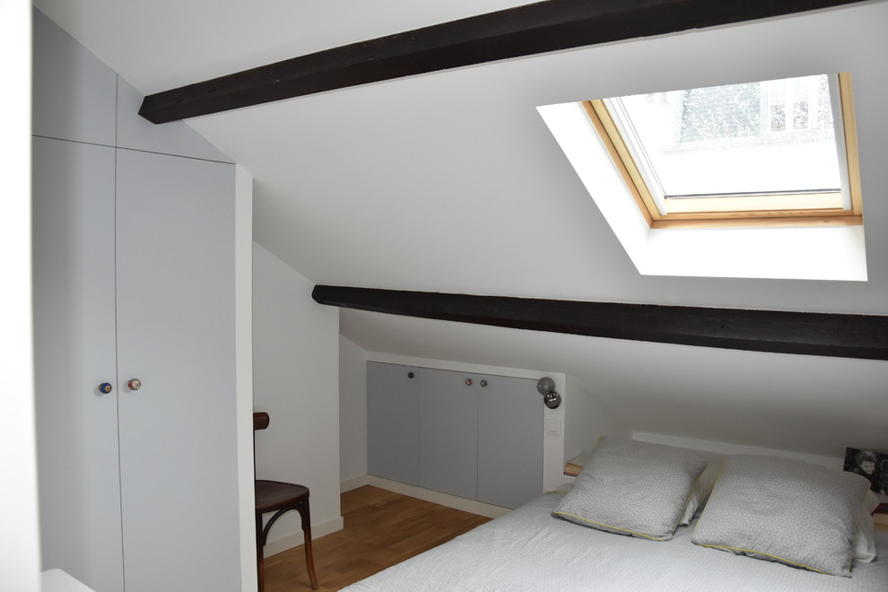 Inspiration for a small midcentury loft-style bedroom in Paris with white walls and light hardwood floors.
