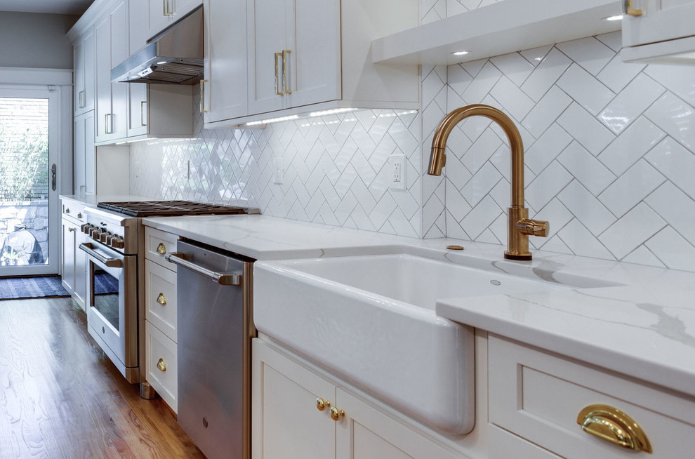 Example of a mid-sized transitional galley light wood floor and beige floor eat-in kitchen design in DC Metro with a farmhouse sink, shaker cabinets, white cabinets, quartz countertops, white backsplash, subway tile backsplash, stainless steel appliances, a peninsula and white countertops