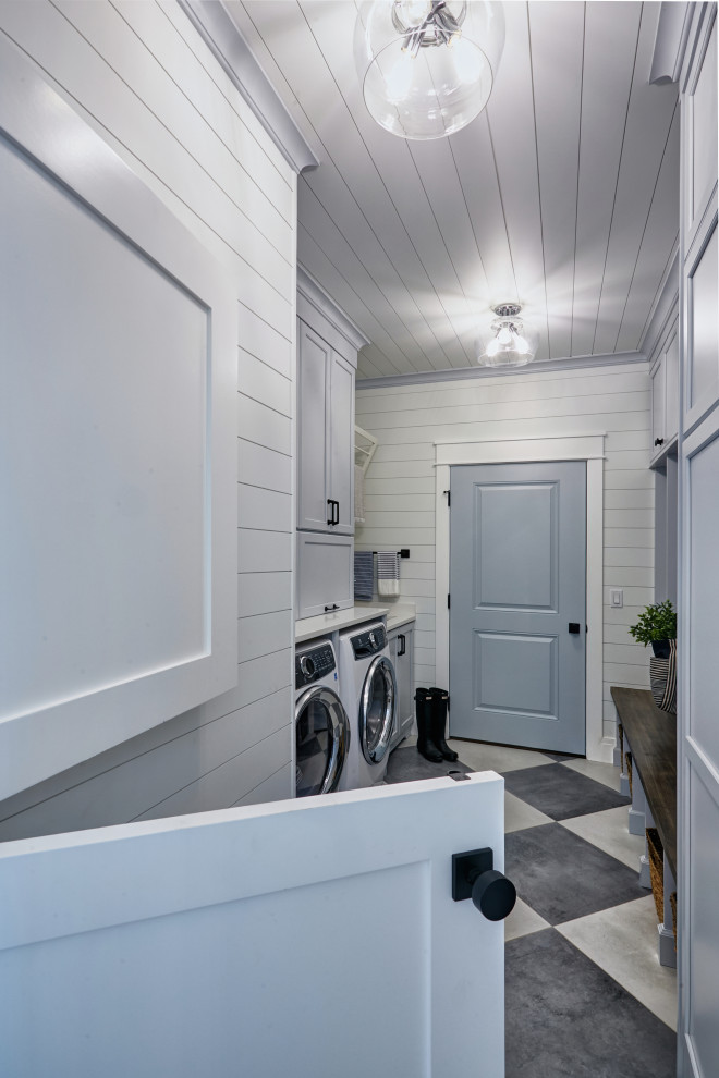 This is an example of a mid-sized beach style galley utility room in Other with an undermount sink, flat-panel cabinets, blue cabinets, quartzite benchtops, white walls, ceramic floors, a concealed washer and dryer, white floor and white benchtop.