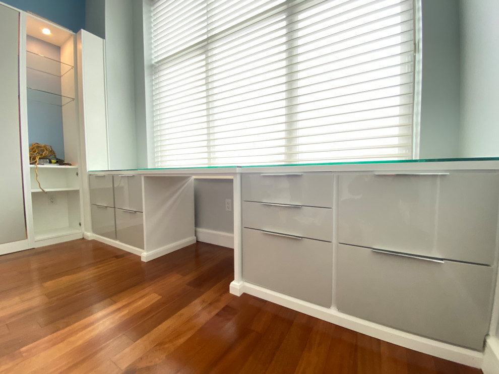 Ejemplo de despacho minimalista con biblioteca, suelo de madera en tonos medios y escritorio empotrado