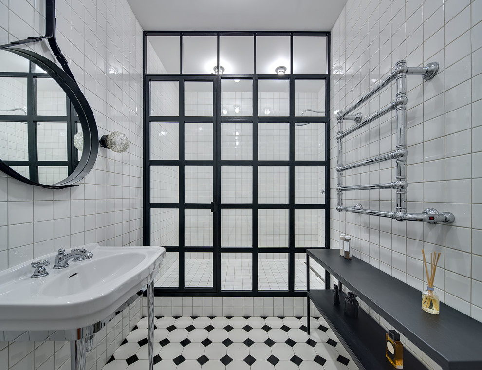 Mid-sized trendy master white tile and ceramic tile ceramic tile, black floor and single-sink alcove shower photo in New York with white cabinets, white walls, a pedestal sink, solid surface countertops, a hinged shower door, white countertops and a freestanding vanity