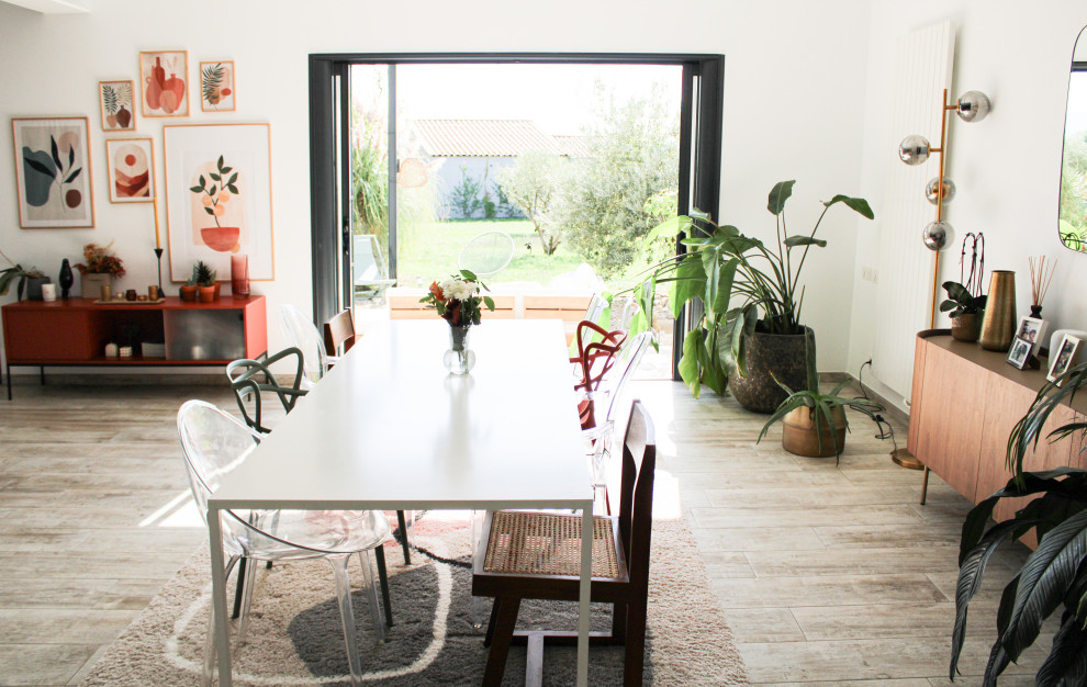 Idee per una sala da pranzo aperta verso il soggiorno minimal di medie dimensioni con pareti bianche, pavimento in laminato, camino sospeso e pavimento beige